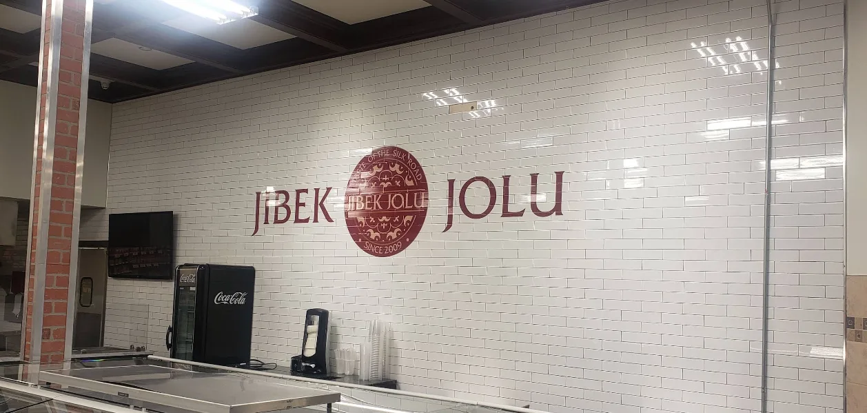 Jibek Jolu counter with tiled wall logo inside Naperville Fresh Market